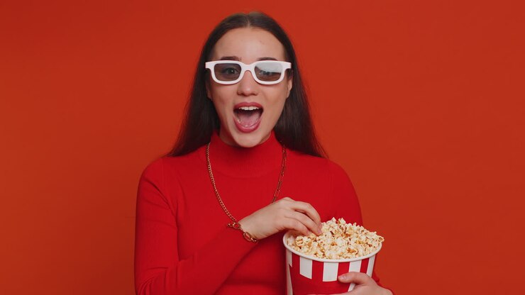 Donna eccitata con occhiali 3D che mangia popcorn e guarda un'interessante serie TV, partita sportiva, film.