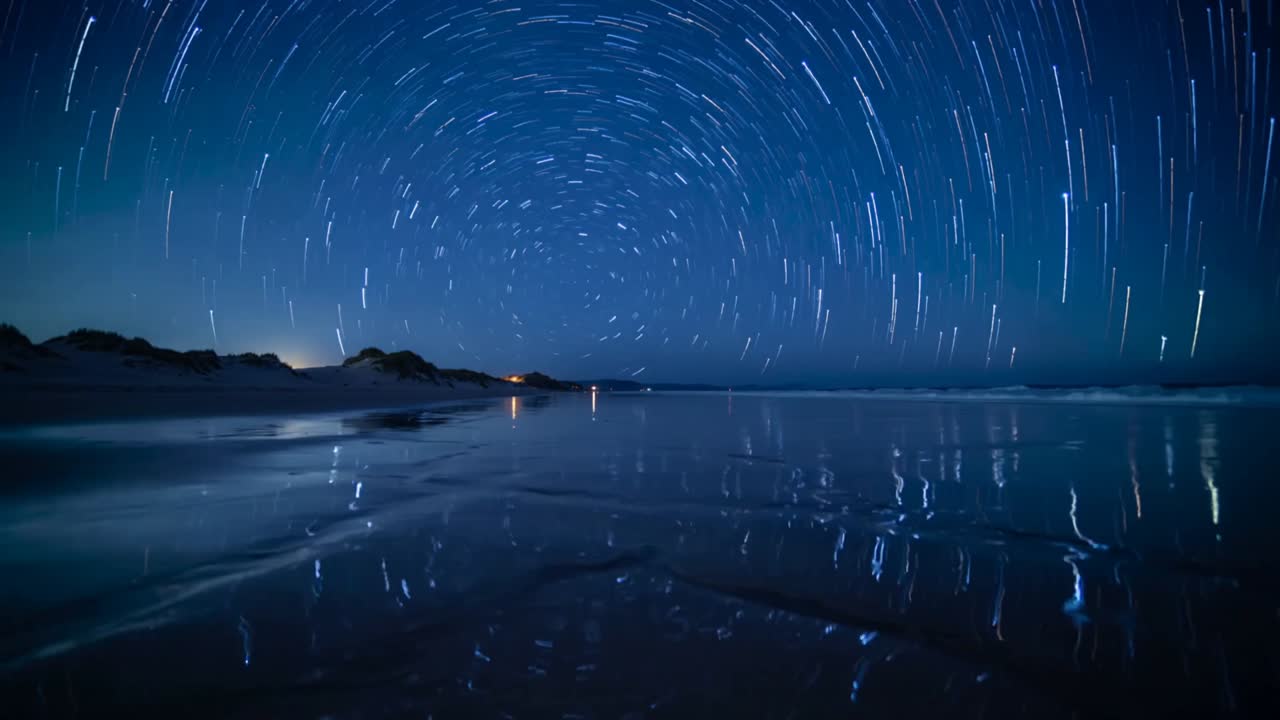Starting timelapse, circular star trails rotating and mirroring on wet sand, showing sky rotation