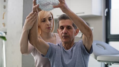 female physical therapist working with senior man at doctor's office.