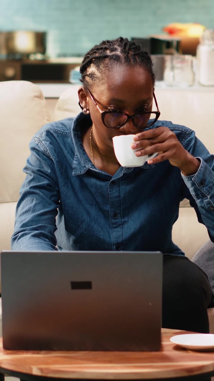 Vertical Video Black woman working remotely from home setup and drinking coffee