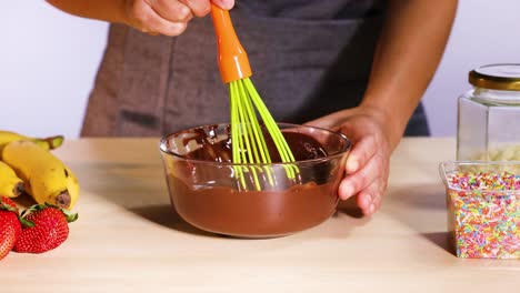 mixing chocolate with fruits and colorful sprinkles