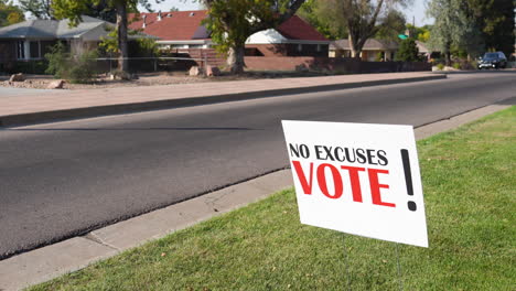 campaign voter rally sign next to road with cars driving by, no excuses vote