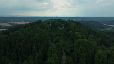 aerial view of a forested hill with a transmission tower. nature with technology broadcasting the signal