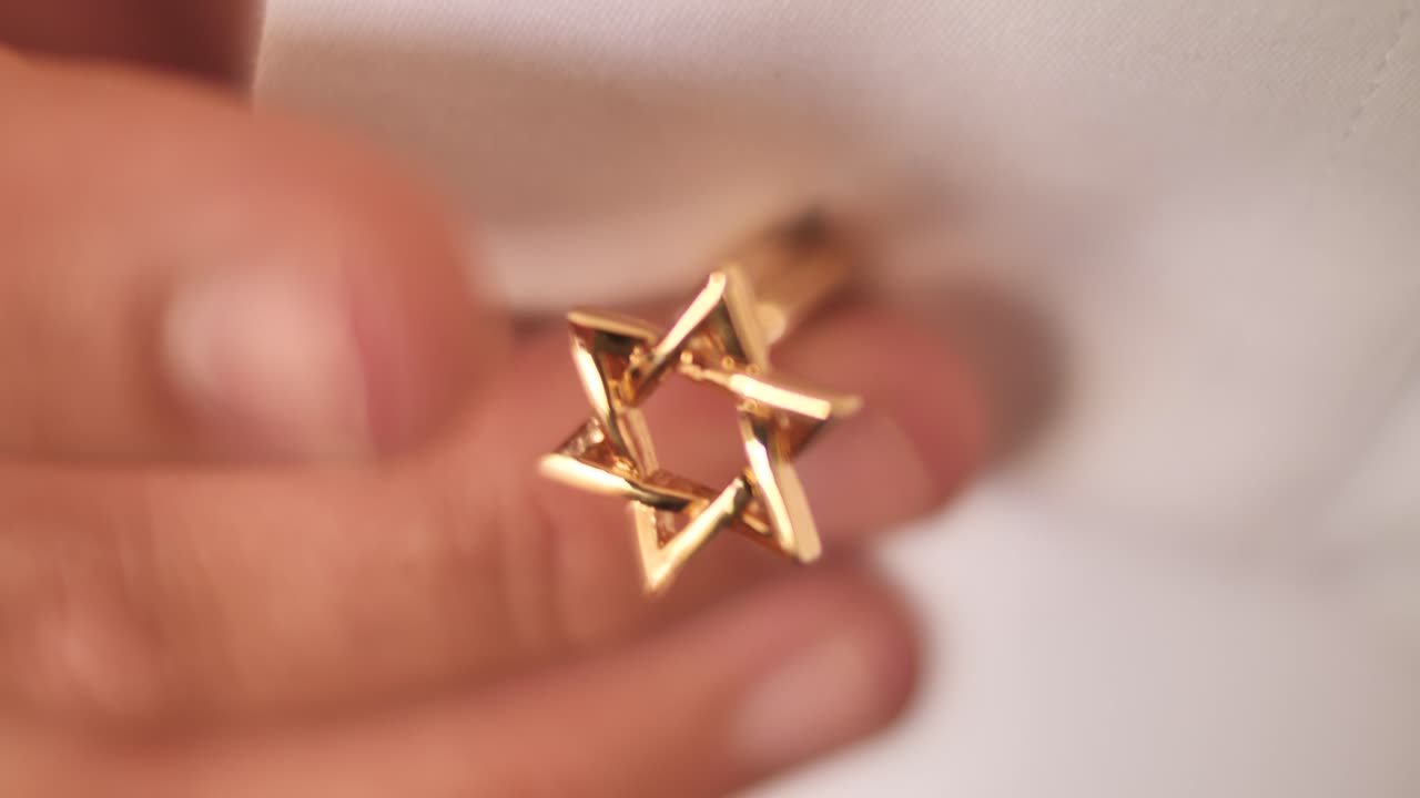 Male wearing David Star shaped golden cufflink on white shirt. Close up