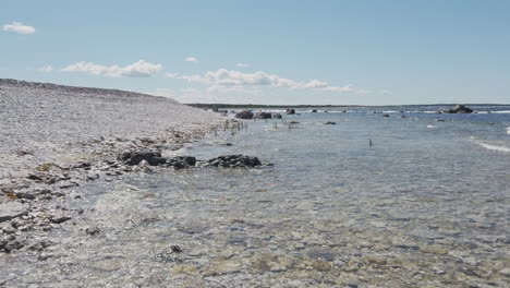 Transparent-water-in-calm-waves-on-the-rocky-beach-on-a-sunny-day