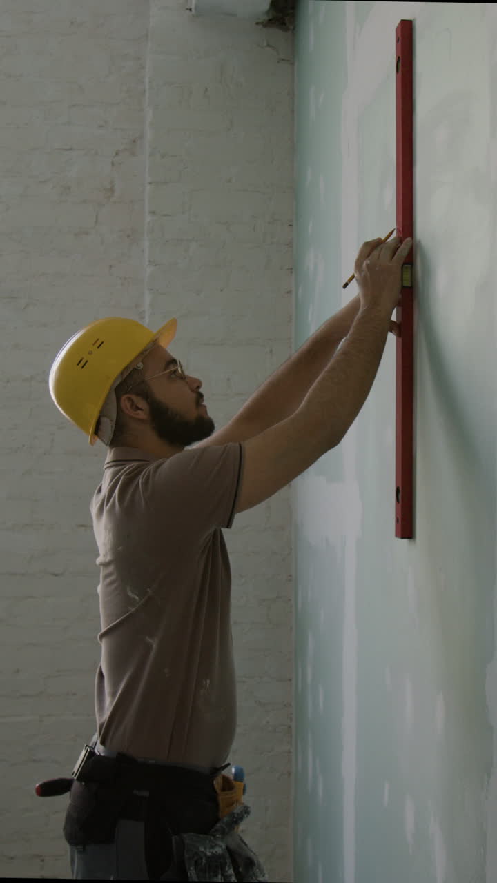Construction worker uses a level to ensure a wall is straight