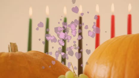 animación de corazones púrpuras sobre velas kwanzaa y calabazas.