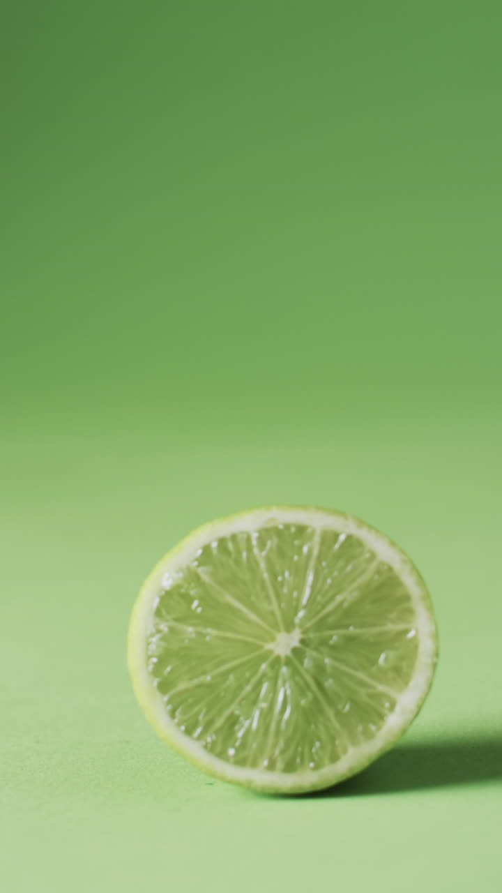 Vertical video of sliced lime with copy space over green background