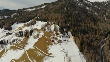 órbita aérea de chalets de madera a lo largo de la idílica cordillera de peitlerkofel y el denso bosque de coníferas