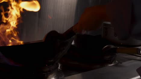chef stir-frying food in a flaming wok