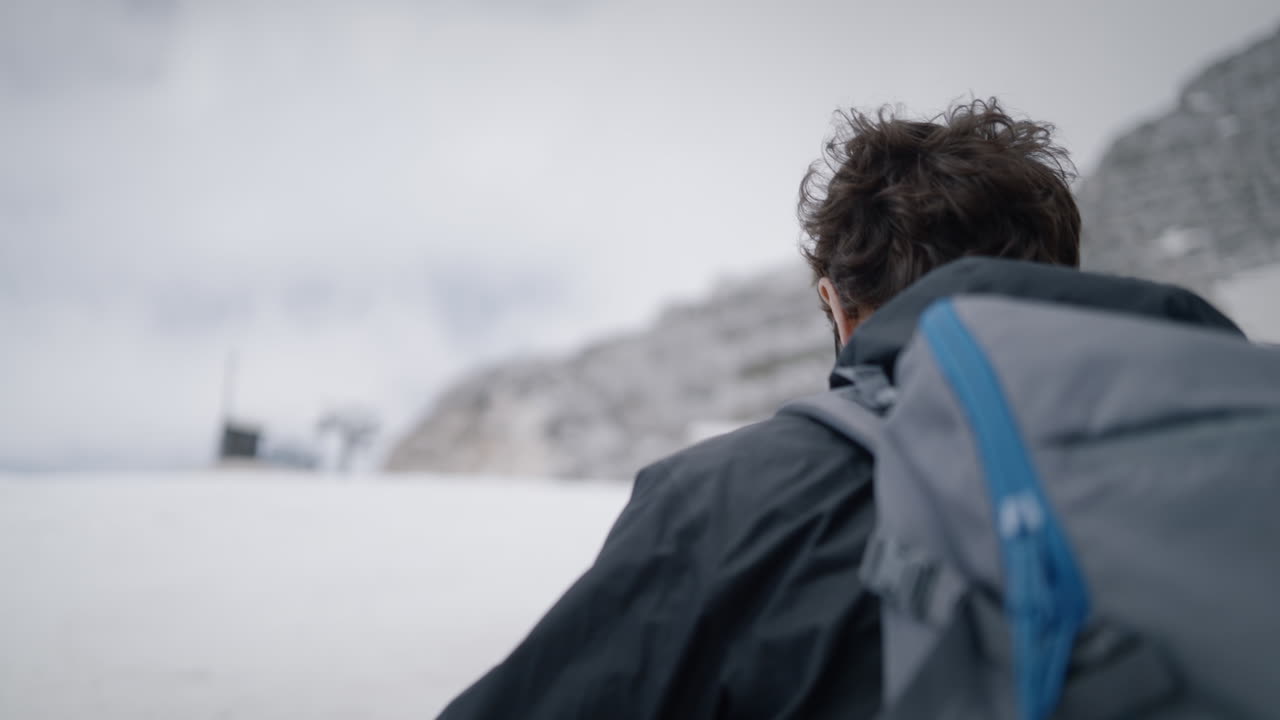 카닌 산을 오르는 카메라 추적 등산객, 그는 배낭을 눈과 바위에 내려놓고 엽니다