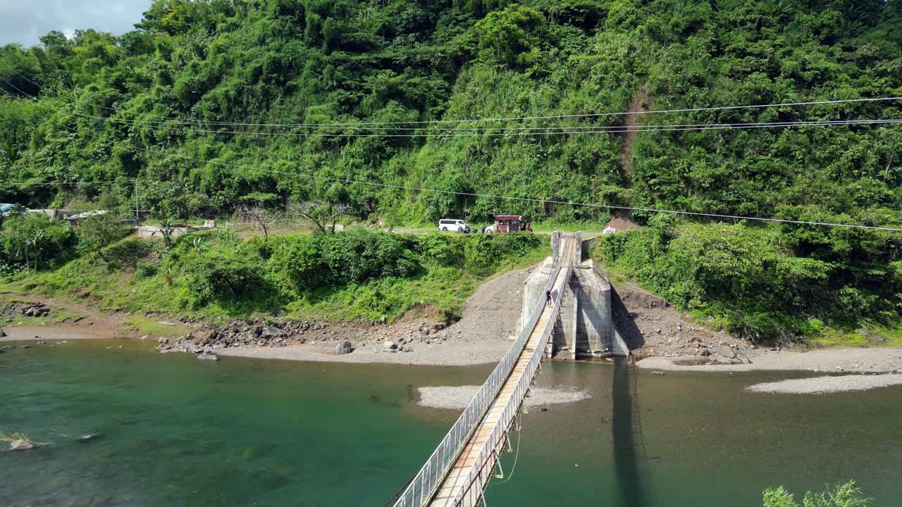 persona caminando en un puente colgante de madera a través del río en catanduanes, filipinas