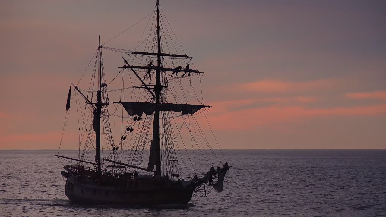 삭구에 선원들과 함께 석양에 항해하는 키 큰 클리퍼 선박