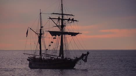 Ein-Großes-Klipperschiff-Segelt-Bei-Sonnenuntergang-Mit-Matrosen-Auf-Der-Takelage