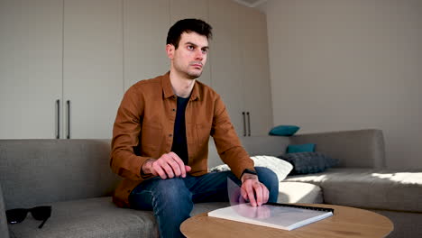 blind man reading a braille book while sitting on sofa at home