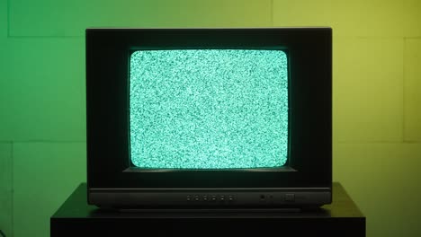 old retro square television on green and yellow neon background, screen with ripples and interference. old-fashioned tv with bad signal reception, tv setting concept, searching channel