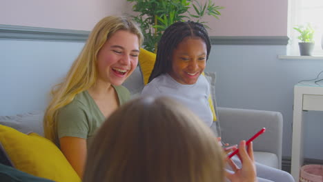 Grupo-De-Amigas-Adolescentes-Multiculturales-Con-Teléfonos-Móviles-Colgando-En-El-Dormitorio-En-Casa