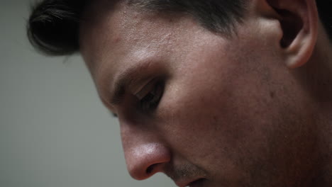 face of a sad, depressed attractive, handsome man, criminal prisoner, inmate in orange jumpsuit sitting in prison cell