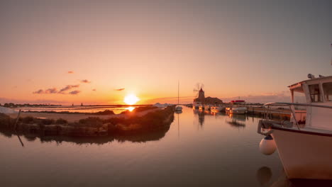 time lapse sunset at salt evaporation ponds with windmill and boats in marsala, italy