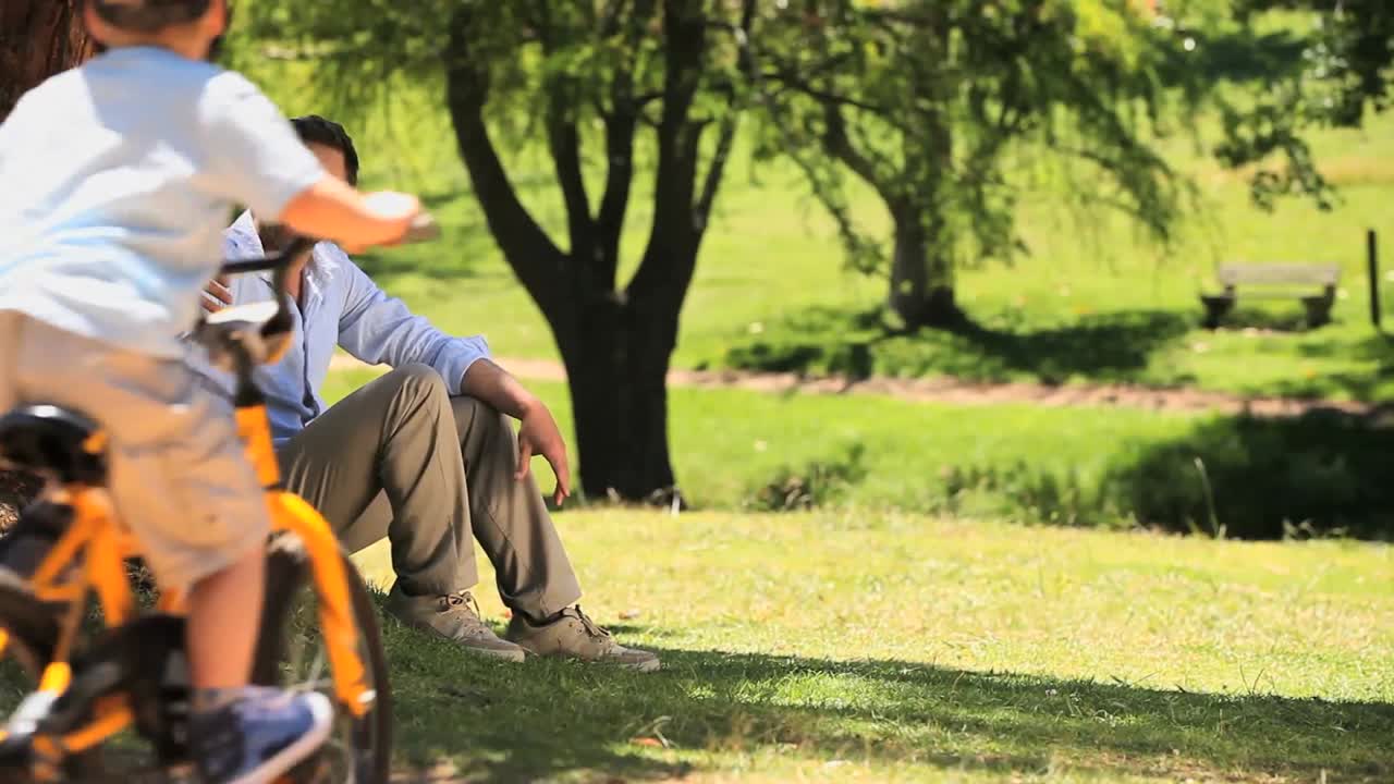 아빠가 자전거를 타는 아들을 보고 있다