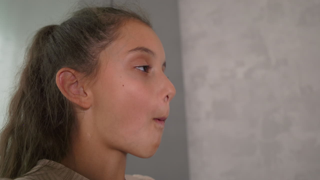 Girl eating sandwich, focused on food, casual breakfast moment, enjoying meal, family atmosphere, soft light from window, relaxed indoor setting, simple joy at home