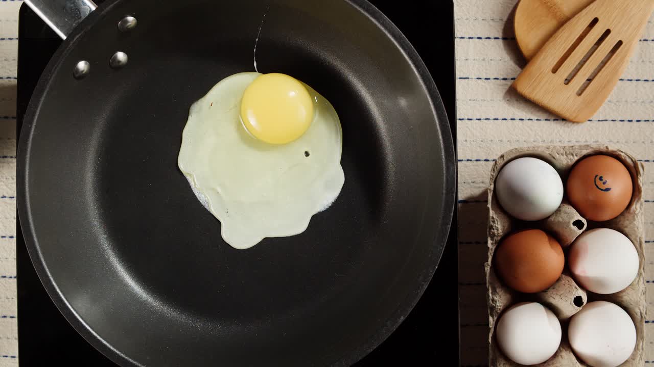 Hand Cracking a Fresh Egg into a Frying Pan