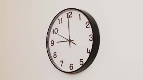 a detailed close-up of a wall clock with a black frame and white face, displaying the time at 9:00.