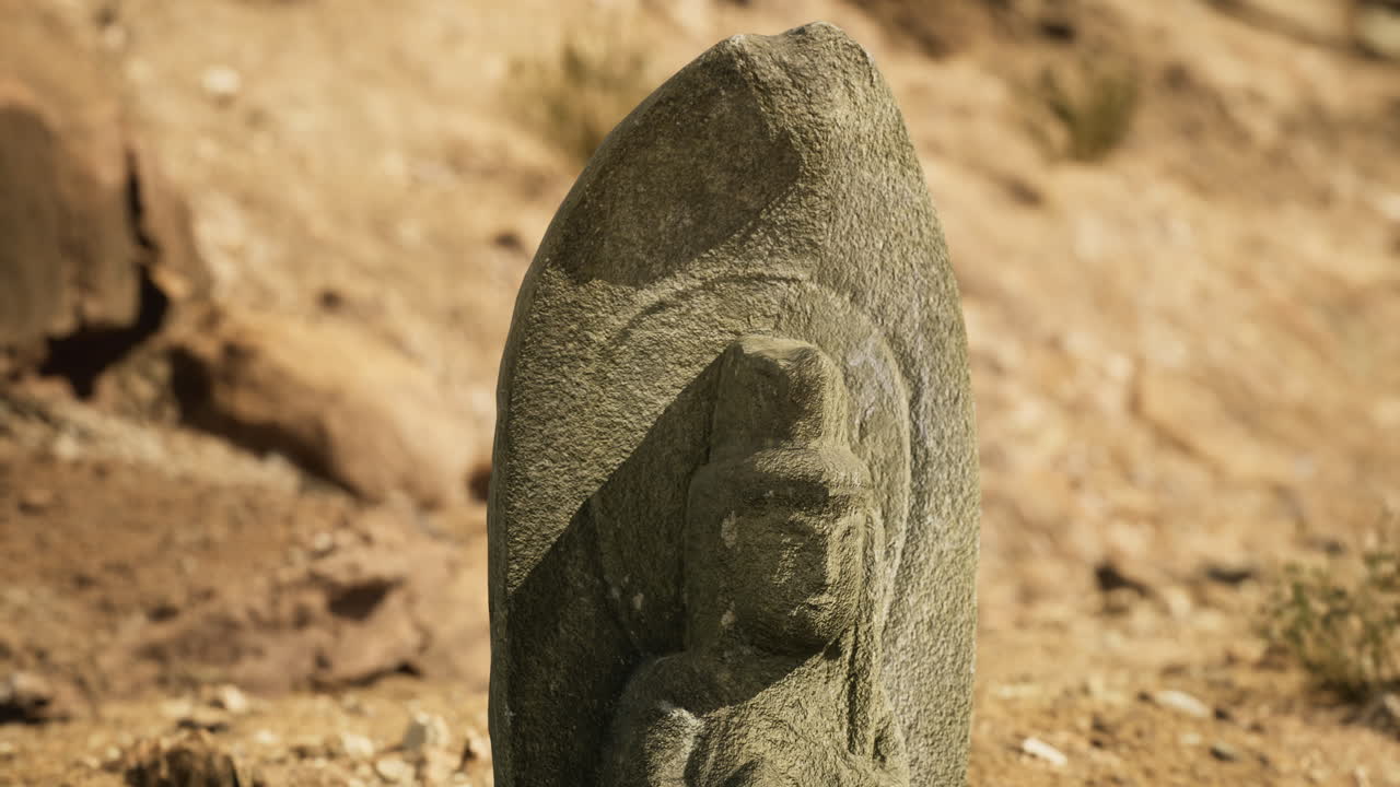 Crafted stone sculpture depicting a figure against a sandy landscape backdrop