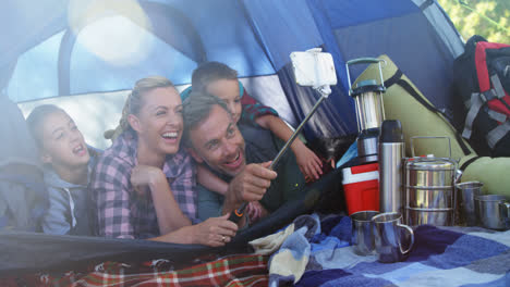 smiling family taking selfie in the tent