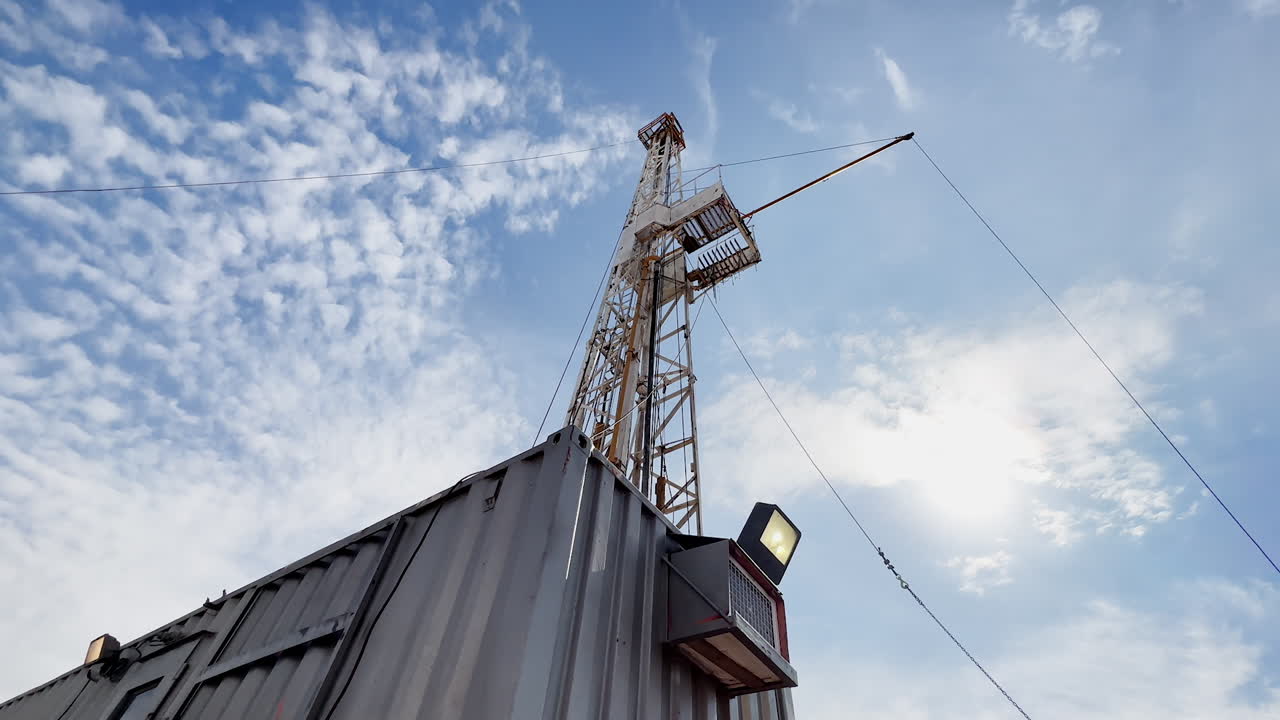 Wagon at the oil production site. Derrick with drilling equipment at backdrop. Low angle view.