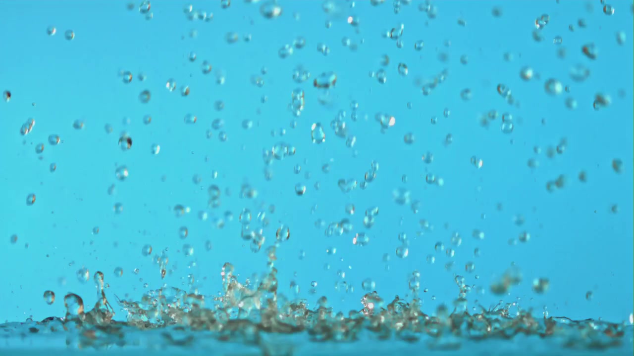 Slow Motion Water Droplets Falling and Splashing on Blue Surface