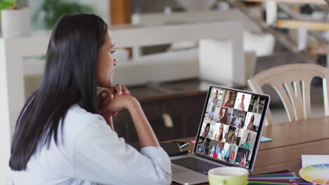 mujer caucásica usando una computadora portátil en una videollamada con colegas que trabajan desde casa