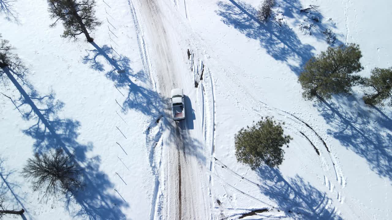 drone sigue camión blanco a la deriva en la nieve cubierta carretera helada resbalando y luego recuperar el control con largas sombras de los árboles