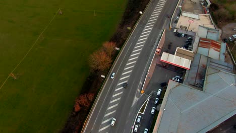 aerial shot of an italian road with moving cars with a petrol station and a field on the sides