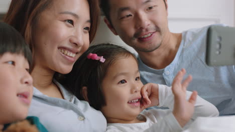 happy-asian-family-having-video-chat-using-smartphone-in-bed-mother-and-father-with-children-waving-chatting-to-friends-on-mobile-phone-enjoying-online-communication-4k-footage