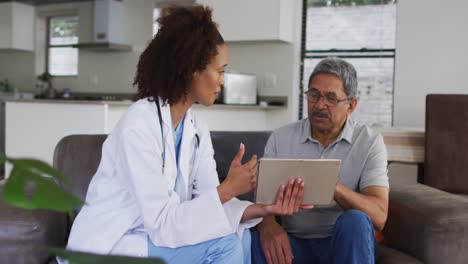 médico de raza mixta y un hombre mayor usando una tableta y hablando