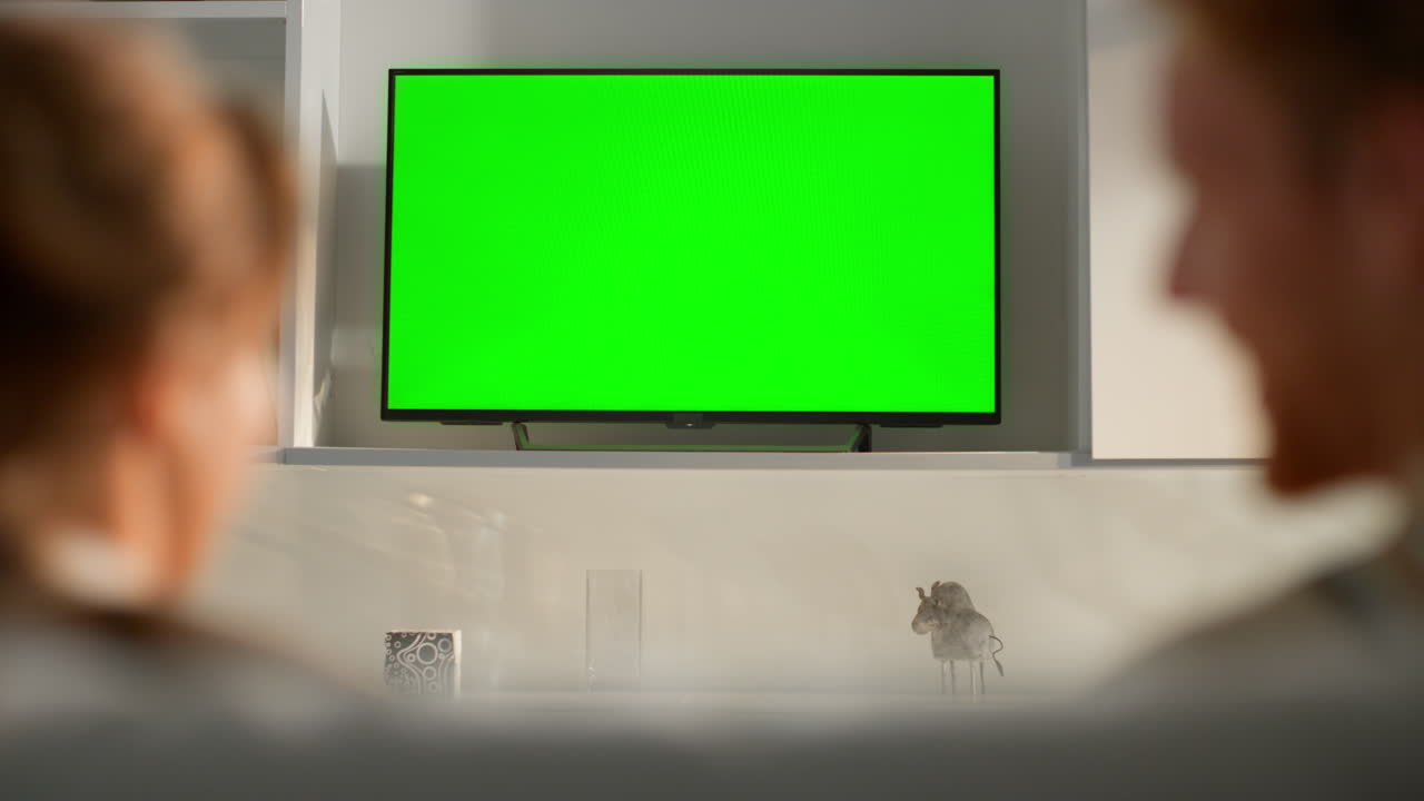 Family watching chroma key TV set in living room. Unknown couple discussing blog
