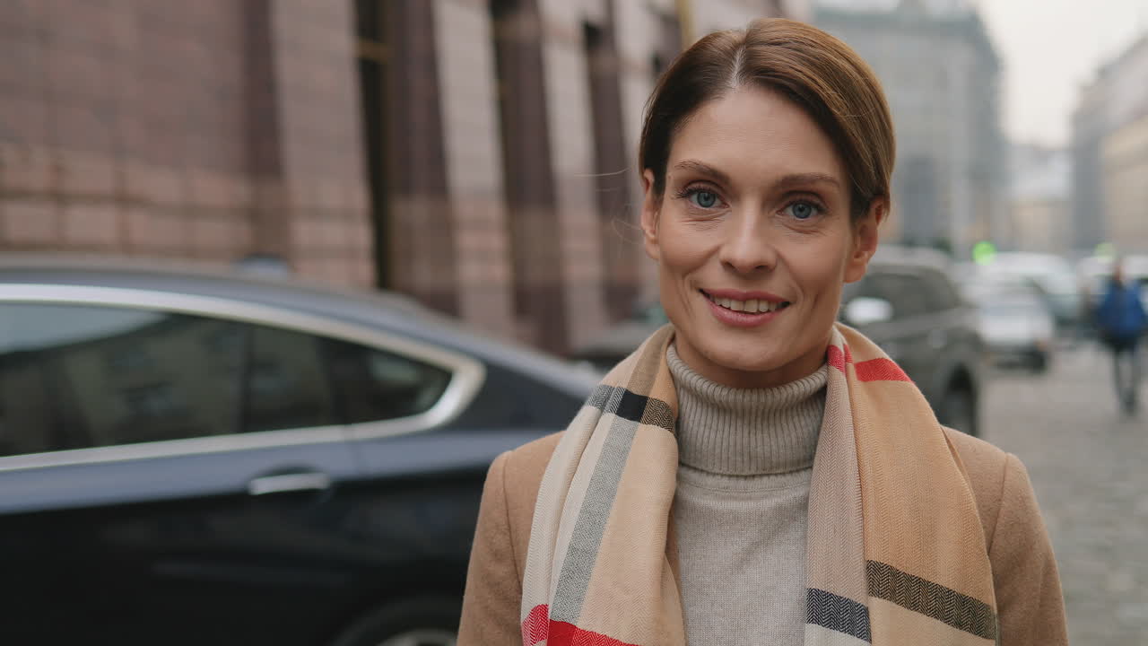 Close-up view of Caucasian businesswoman looking at the camera and smiling in the street in autumn