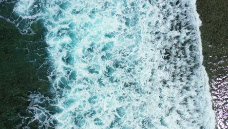 dramatic sea scenery of big white waves splashing on shore with corals and rocks, foaming over calm lagoon, creating sea texture