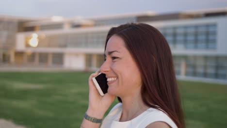 mujer emocional hablando en el teléfono inteligente mientras caminaba por la calle.