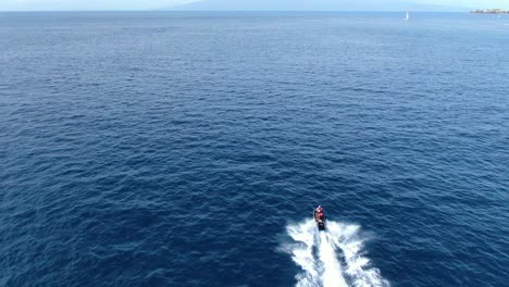 drone following two people riding a jetski in the hawaiian ocean