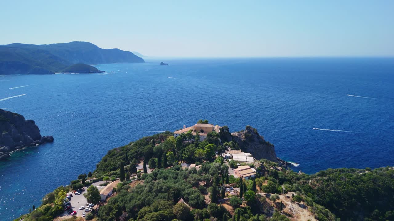 Aerial view of rocky coastline, lush greenery, and deep blue sea under clear sky