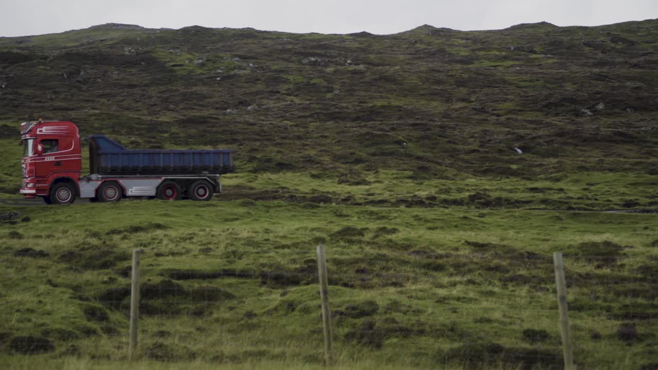 Wide shot showing driving truck on scenic road between hills on Vagar Island,Faerose.Slow motion.