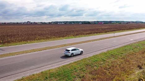 aerial view on white audi moving on the highway. top view of luxury car driving slowly on the background rural area at day time.