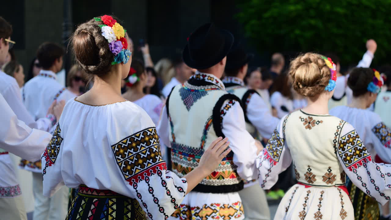 A group of folk dancers showcases vibrant traditional costumes and engaging choreography at a cultural festival held in a park. Wearing traditional Moldavian costumes