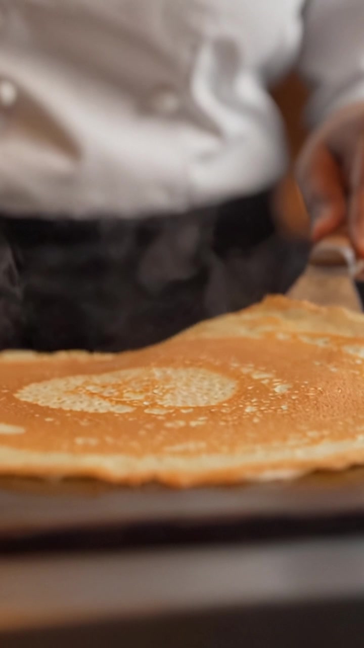 Chef esperto prepara con maestria deliziose crepes in una cucina moderna, mettendo in mostra deliziose tecniche culinarie e un perfetto equilibrio di sapori in ogni fase.