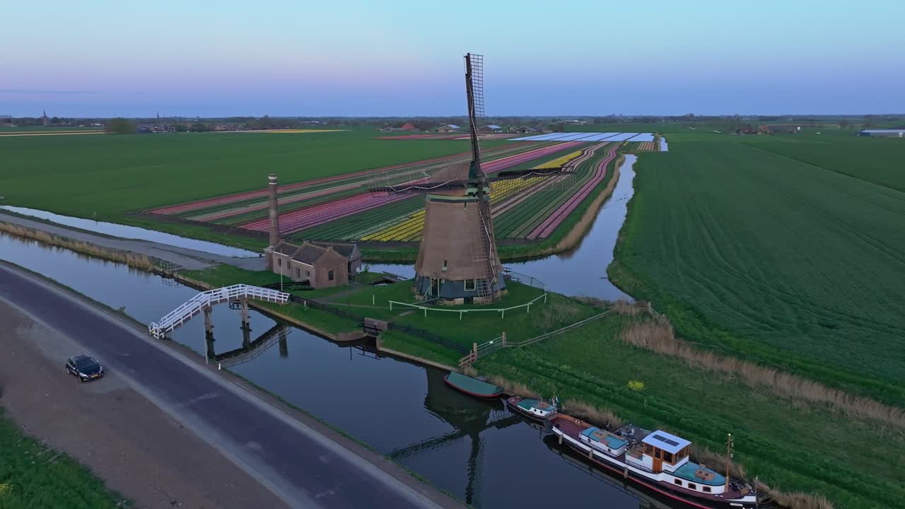 Vista aerea di campi di tulipani colorati con il mulino a vento de Kaagmolen nella morbida luce del crepuscolo
