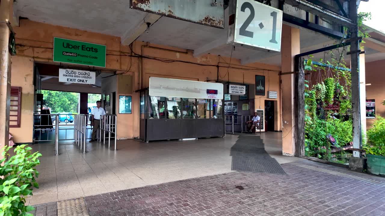 Local commuters make their way through the entrance of Kandy Station. The busy platform features a mix of traditional and modern architecture, providing a transit hub atmosphere.