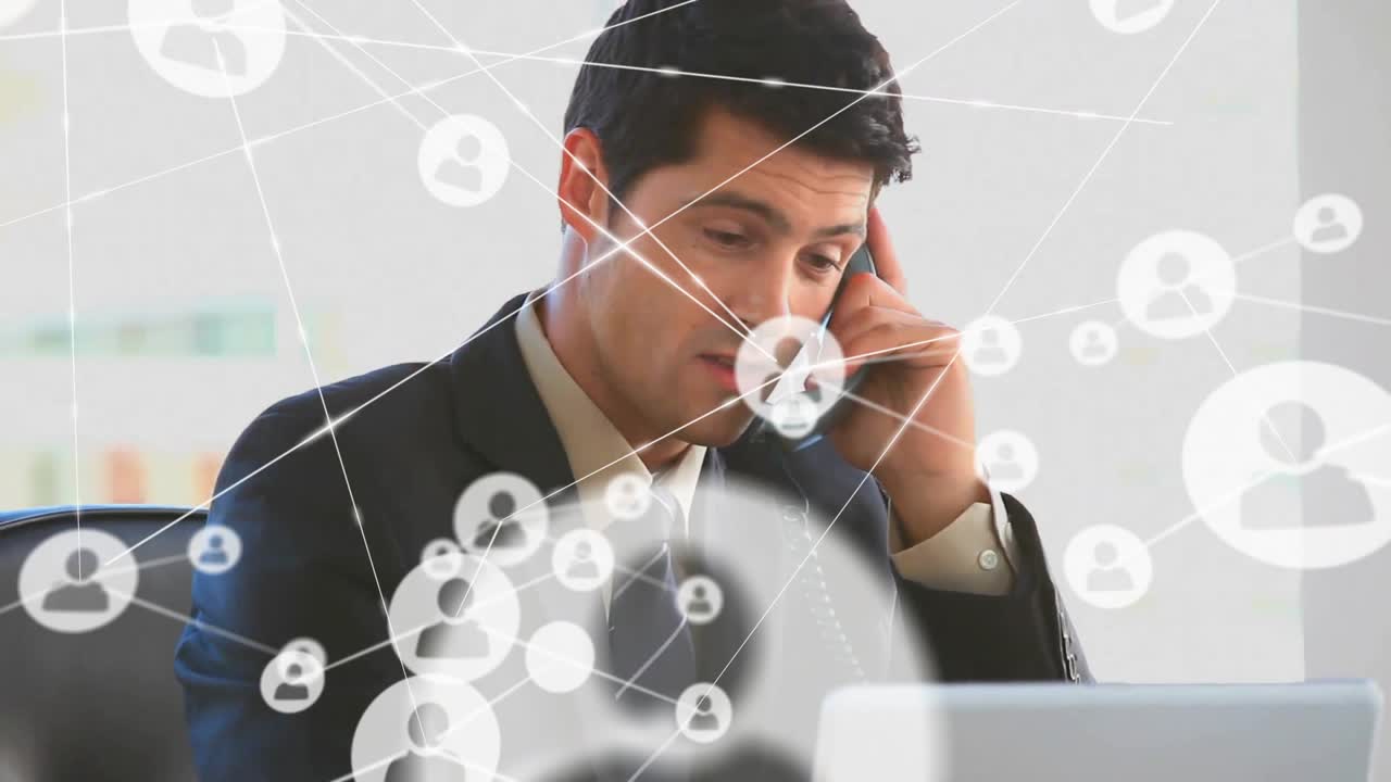 Animation of connected icons over caucasian businessman talking on phone while working on laptop