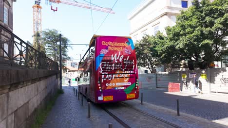 a colorful double-decker tour bus drives through a sunny street in porto, portugal